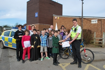 PCSO Alex Morrison presents Harry Goodhall with his certificate. In the background are Sergeant Frances Hannan, head teacher Richard Wild and other children from the school